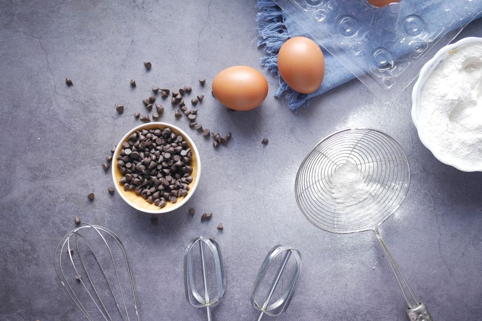 Top view of baking essentials with chocolate chips, eggs, and flour on a countertop.